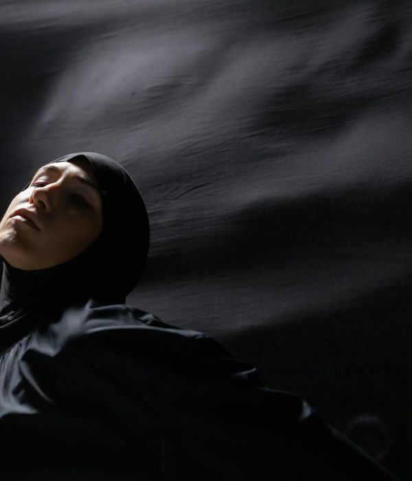 Woman performing a graceful yoga flow pose in a dark studio.